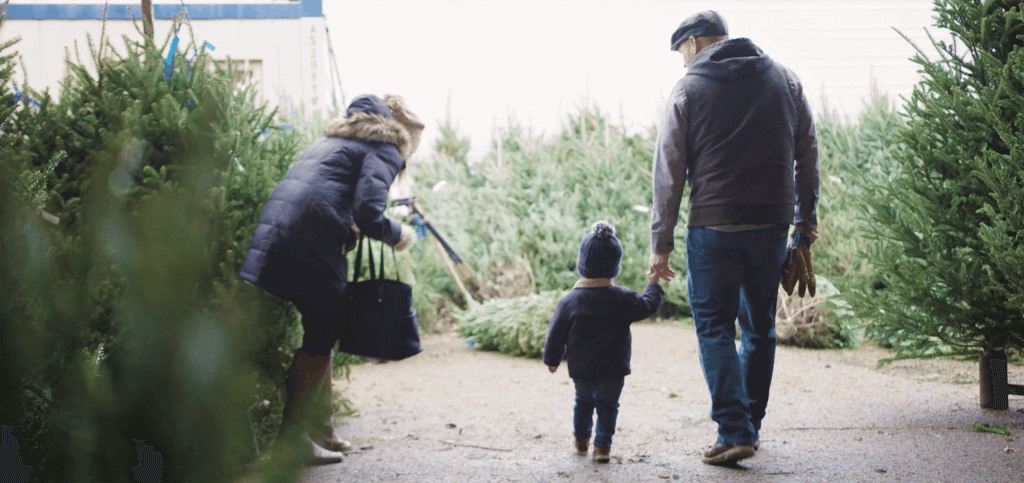 Two parents standing with their child at a tree farm